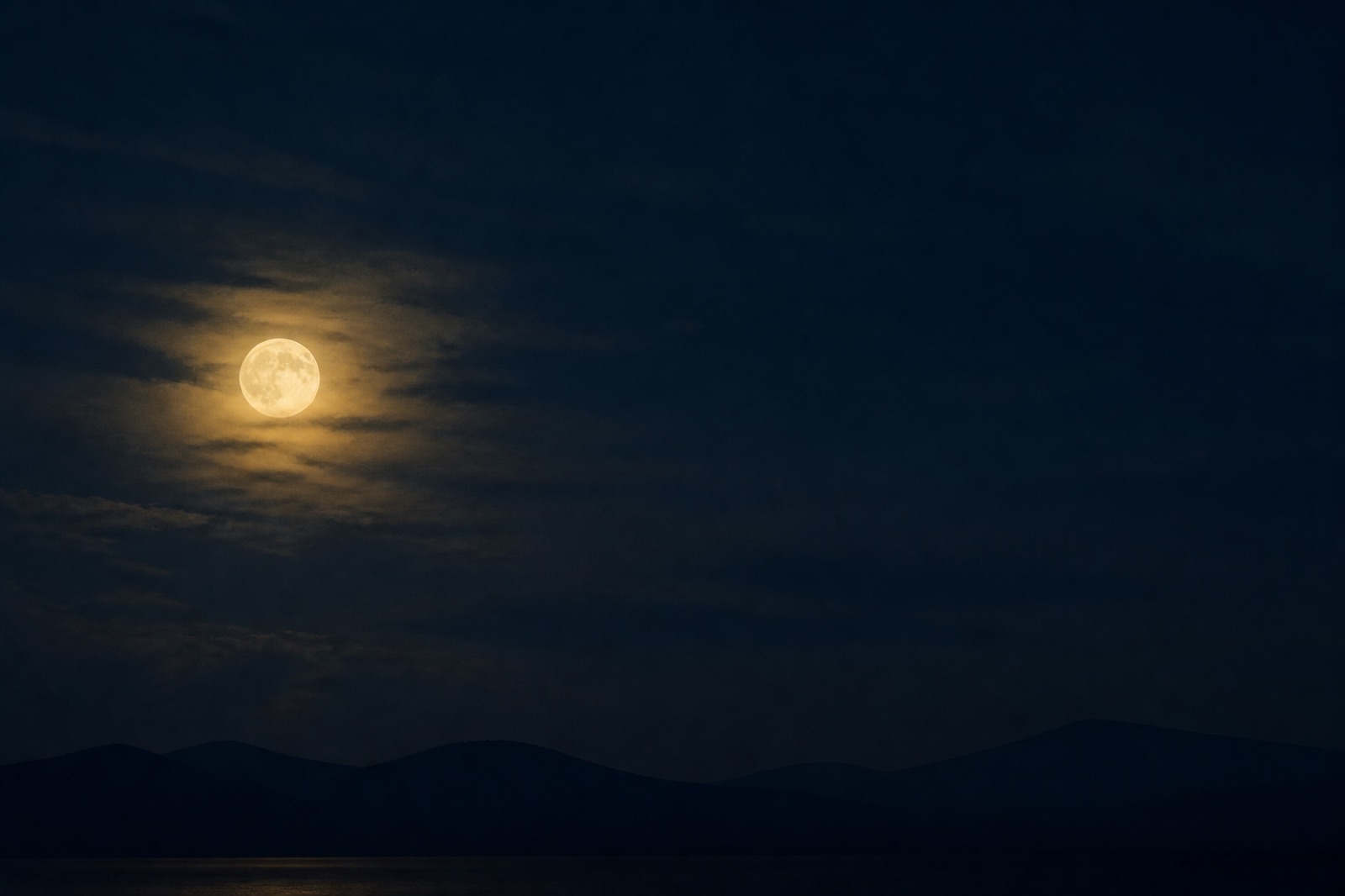 Vollmond über nächtlicher Hügellinie